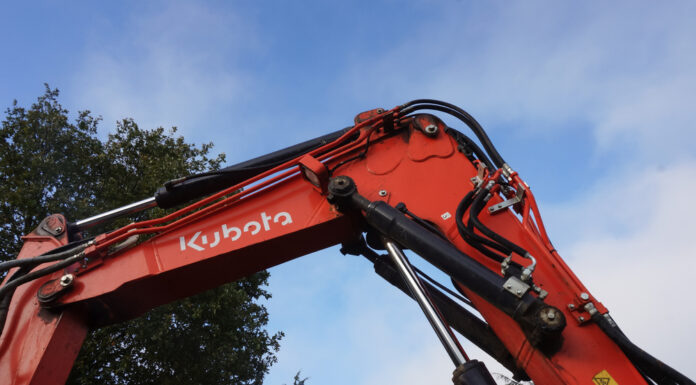 Kubota to invest $140M in new Georgia factory, hiring 500 Georgia, Kubota, Factory: red crane arm with wires in front of green leafy tree with clouds