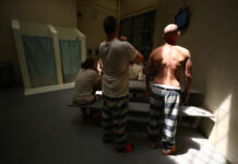 Information about COVID-19 in jails is lacking nationwide Men in jail with white and black striped pants and their shirts off facing away from the camera