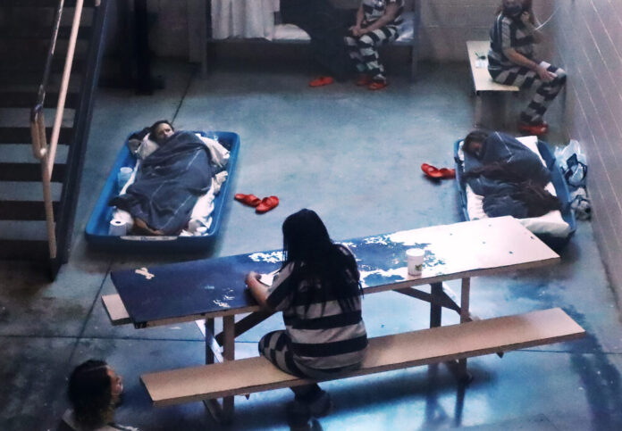 scene shot from above inside a jail cell with at least five female inmates