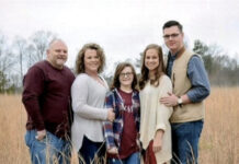 Remembering lives lost during the coronavirus pandemic a white family of five stands in wheat field in warm clothes during fall