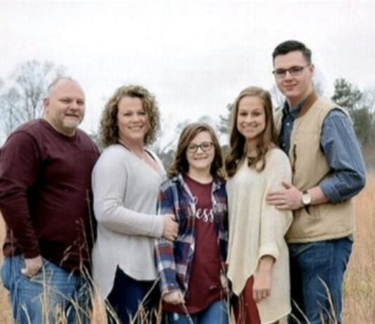 Remembering lives lost during the coronavirus pandemic a white family of five stands in wheat field in warm clothes during fall