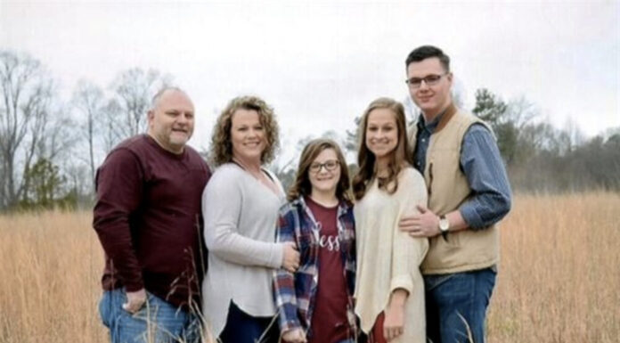 Remembering lives lost during the coronavirus pandemic a white family of five stands in wheat field in warm clothes during fall