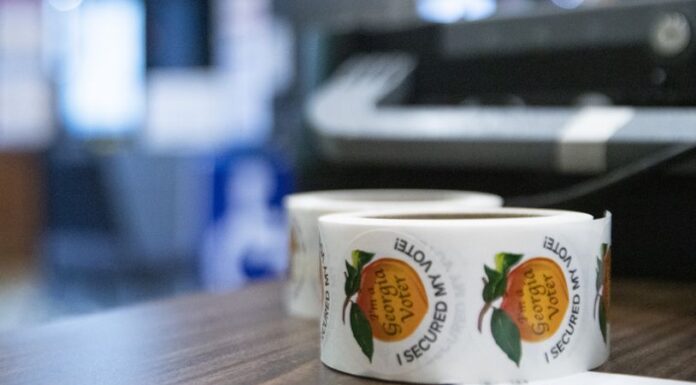 What do you want Georgia political candidates to talk about? Roll of Georgia voter peach stickers on a brown table with a blurred background