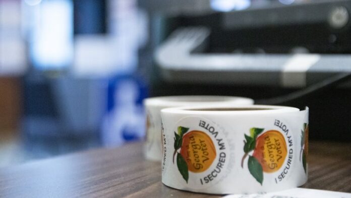 Roll of Georgia voter peach stickers on a brown table with a blurred background