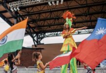 International festival returns to Lawrenceville larger than last year two little girls walking in front of stilt performer waving colorful international flags outside