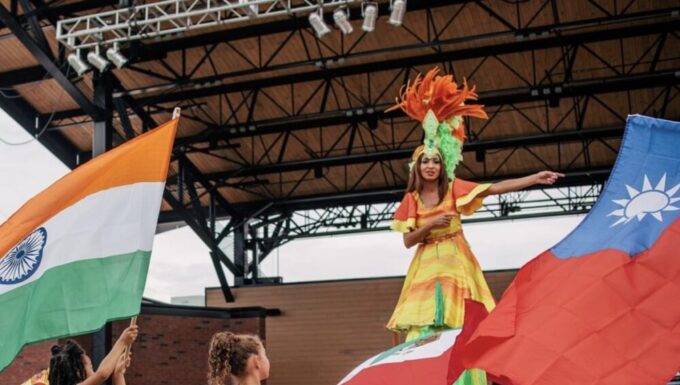International festival returns to Lawrenceville larger than last year two little girls walking in front of stilt performer waving colorful international flags outside