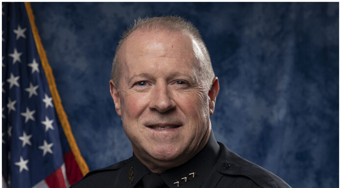 Marietta hires department veteran Martin Ferrell as police chief headshot of white man in police uniform in front of blue background with flag