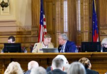 AJC poll: Georgians oppose runoffs, back sports betting and abortion rights Four people sitting behind podium desk behind computers talking in a courtroom with an American flag in the background.