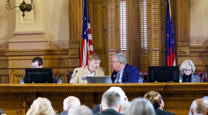 AJC poll: Georgians oppose runoffs, back sports betting and abortion rights Four people sitting behind podium desk behind computers talking in a courtroom with an American flag in the background.