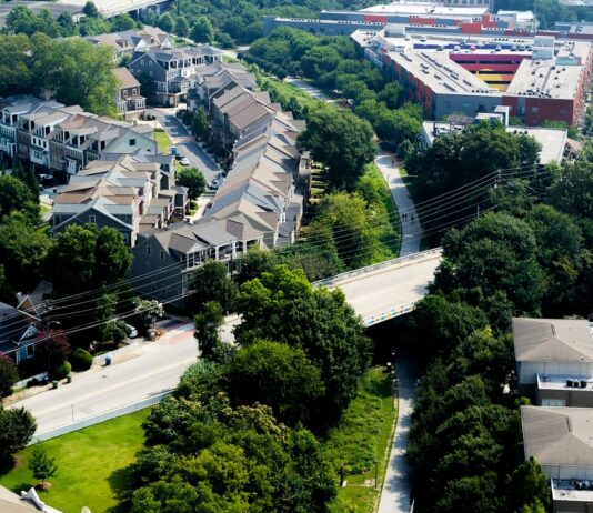 Atlanta’s BeltLine shows how urban parks can drive ‘green gentrification’ if cities don’t think about affordable housing at the start Aerial view of paved out pathway surrounded by green trees and housing to the left of the path