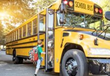 Metro Atlanta school districts grapple with teacher shortages child wearing green shirt and red backpack boards a yellow school bus