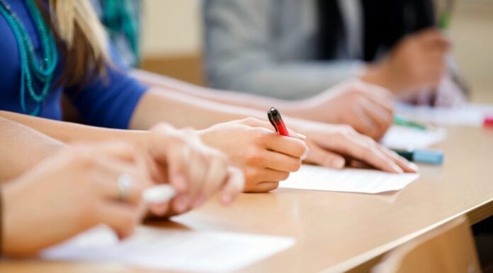 Georgia students again best the nation on SAT Students at a desk taking notes on paper with pens