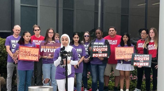 Cobb County students organize against divisive concept bans Woman in hijab speaks outside in front of microphone with a group of supporters behind her in casual clothes