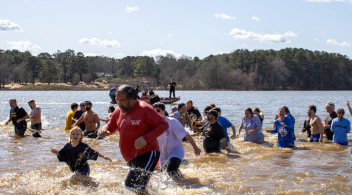Freezin’ for a reason: Georgia Special Olympics finds fundraising success A group of people run out of a lake on a clear day. Water splashes around their legs.