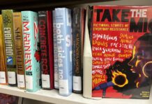 Georgia Senate targets American Library Association in new legislative push A row of multicolored books are lined up on a plain shelf. All have their spines facing the camera. On the right, the book "Take the Mic: Fictional Stories of Everyday Resistance" is turned so the cover faces the camera. The cover is red, the title is in black and white, and it features an illustration of a side profile of a Black woman yelling into a microphone that is on fire. There are 11 authors whose names are scattered across the cover.