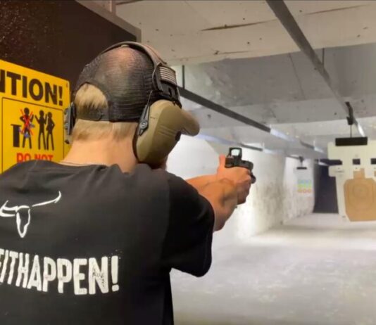 Georgia Senate waives sales tax for improved firearm safety A man shoots a pistol in a gun range. He is facing away from the camera and wearing a baseball hat, black t-shirt, and large headphones. He is aiming the pistol at a target. A large yellow sign reads "ATTENTION" behind him and shows gun safety advice.