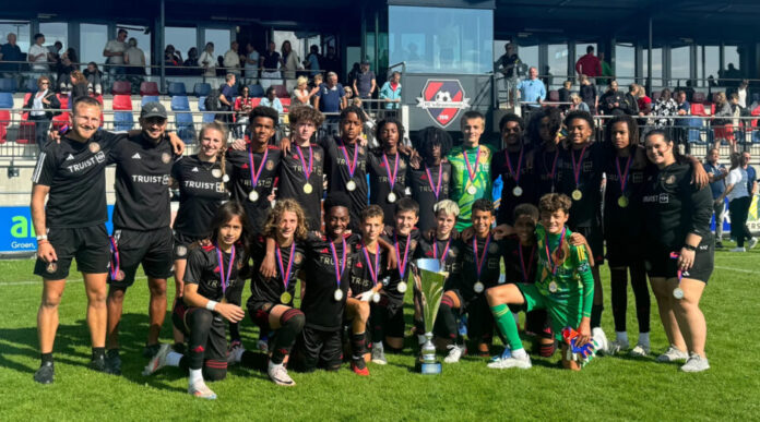 A large soccer team made up of teenage boys wearing black 