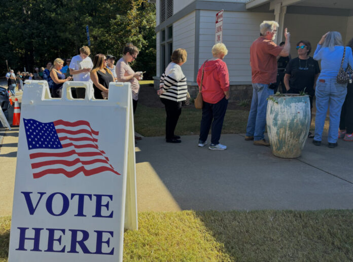 In the foreground, a white standing sign features an American flag and large blue text reading, 