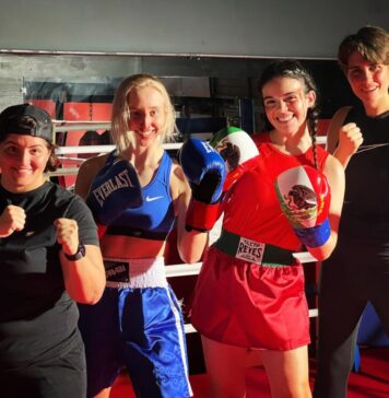 High falls and high stakes: Stuntwomen shaping the entrepreneurial world Four women stand with their fists raised, smiling at the camera. On the far left, the shortest woman wears a backwards hat and a black t-shirt. To her right is a blonde woman wearing a matching blue workout set and blue boxing gloves. Next to her is a girl with blood on her temple wearing a red matching set with braids and boxing gloves of the Mexican flag. Lastly, on the far right, a tall woman with short hair wears a black tank top and leggings.
