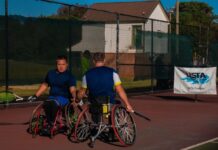 Heart and skill on display at USTA Wheelchair Tennis Championship Two men in wheelchairs dressed in athletic-wear holding tennis rackets high-five each other on a tennis court. There is a banner behind them that reads, "USTA, find yourself in the game, Southern."