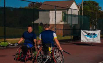 Heart and skill on display at USTA Wheelchair Tennis Championship Two men in wheelchairs dressed in athletic-wear holding tennis rackets high-five each other on a tennis court. There is a banner behind them that reads, "USTA, find yourself in the game, Southern."