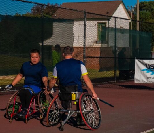 Heart and skill on display at USTA Wheelchair Tennis Championship Two men in wheelchairs dressed in athletic-wear holding tennis rackets high-five each other on a tennis court. There is a banner behind them that reads, "USTA, find yourself in the game, Southern."