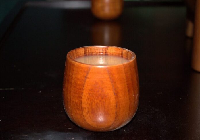 a close-up image of a round wooden cup filled with murky brown-grey liquid.