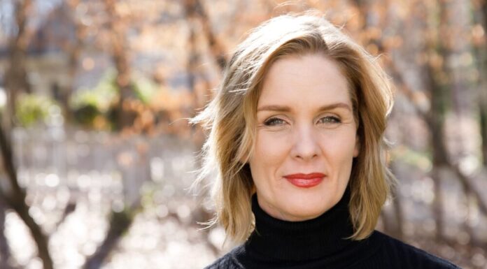 Everyday Hero: Healthcare reformer empowers eczema patients, TSW awareness A headshot of a white woman with shoulder-length blonde hair wearing a black turtleneck. She is standing in front of a blurred background of trees.