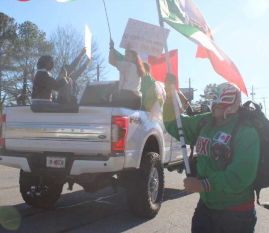 Protestors in Chamblee march against Trump’s deportation orders A protester dressed as a Wrestler running with the flag of Mexico. (Zaire Breedlove/ Fresh Take Georgia)