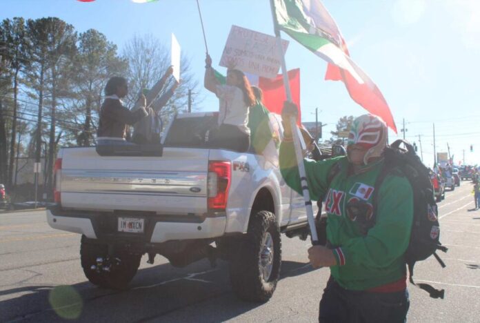 A protester dressed as a Wrestler running with the flag of Mexico (Zaire Breedlove/ Fresh Take Georgia).